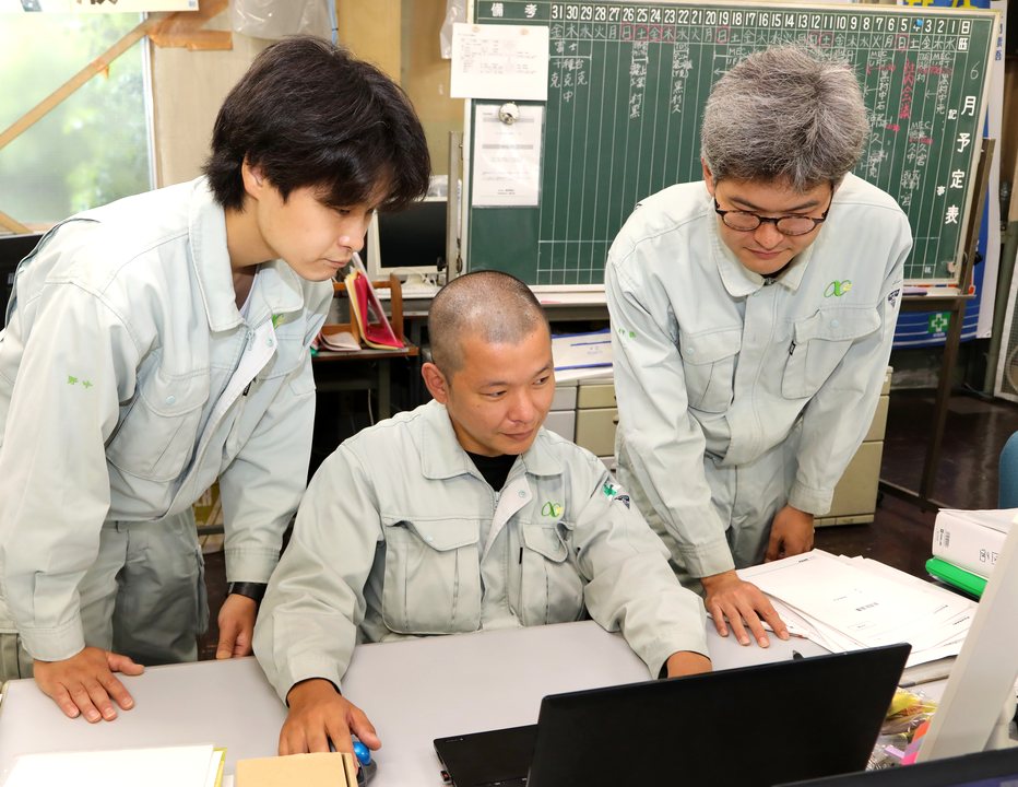 先輩に教わりながら画面を確認する社員
